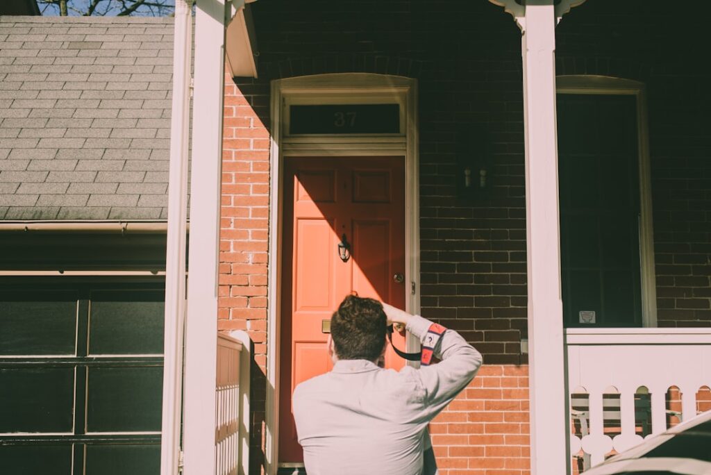 A person closely examining a window frame and wall for stains and signs of moisture inside a home.