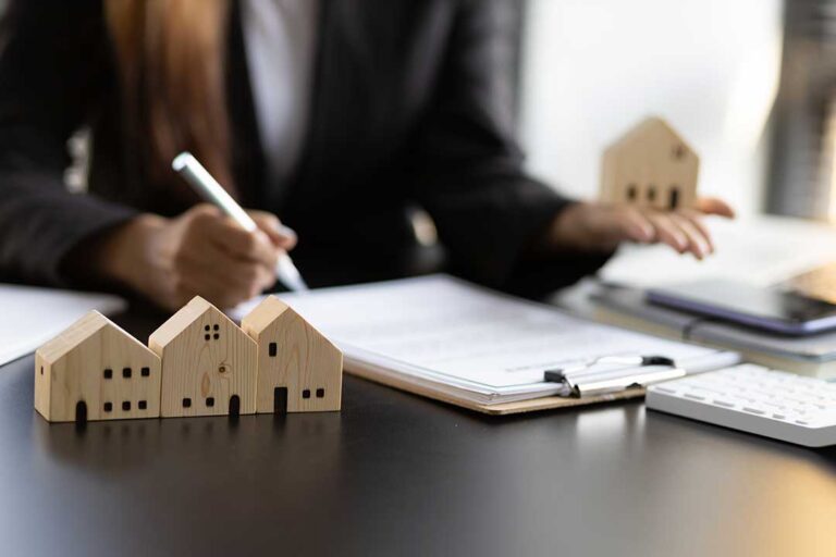 An appraiser reviews a house exterior while holding a clipboard and comparing property details with sales records.